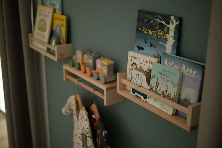 two wooden shelves with books and toys on them in a room next to a window