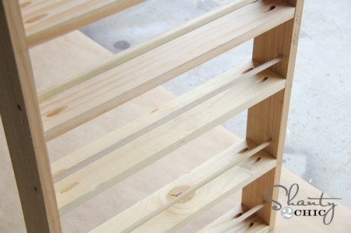 a wooden shelf sitting on top of a floor next to a white tile countertop