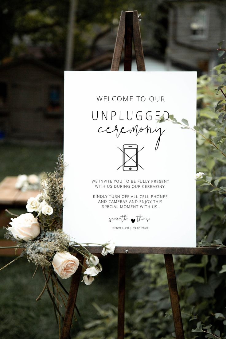 an unplugged ceremony sign with flowers and greenery on the easel