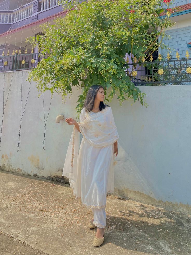 a woman standing under a tree in front of a building