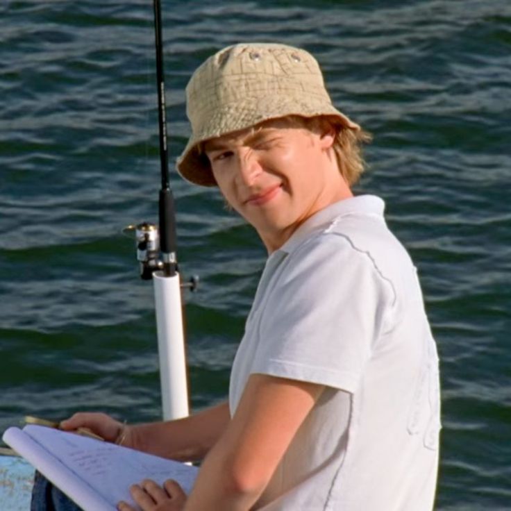 a young boy is sitting on a boat with a fishing pole and paper in his hand