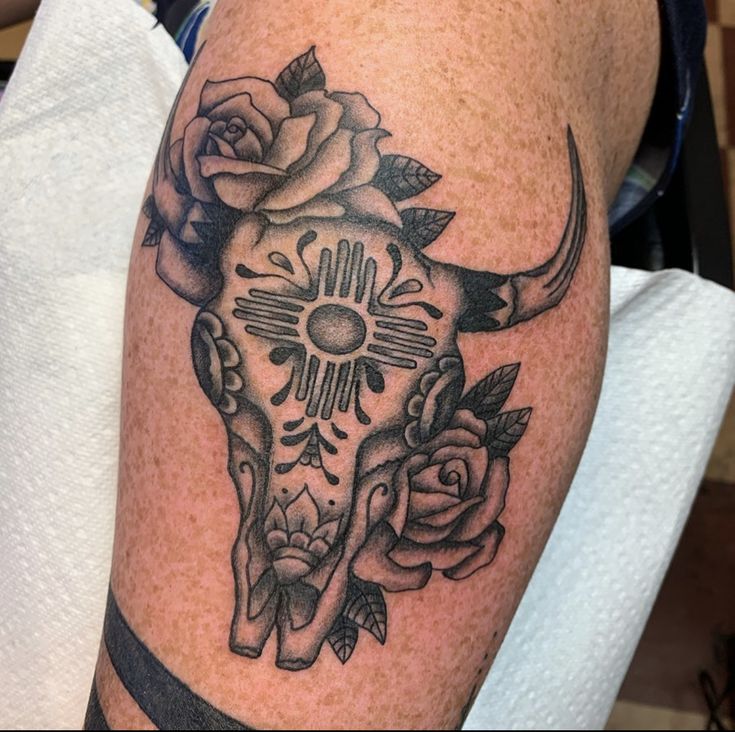 a tattoo on the leg of a person with a cow skull and roses around it