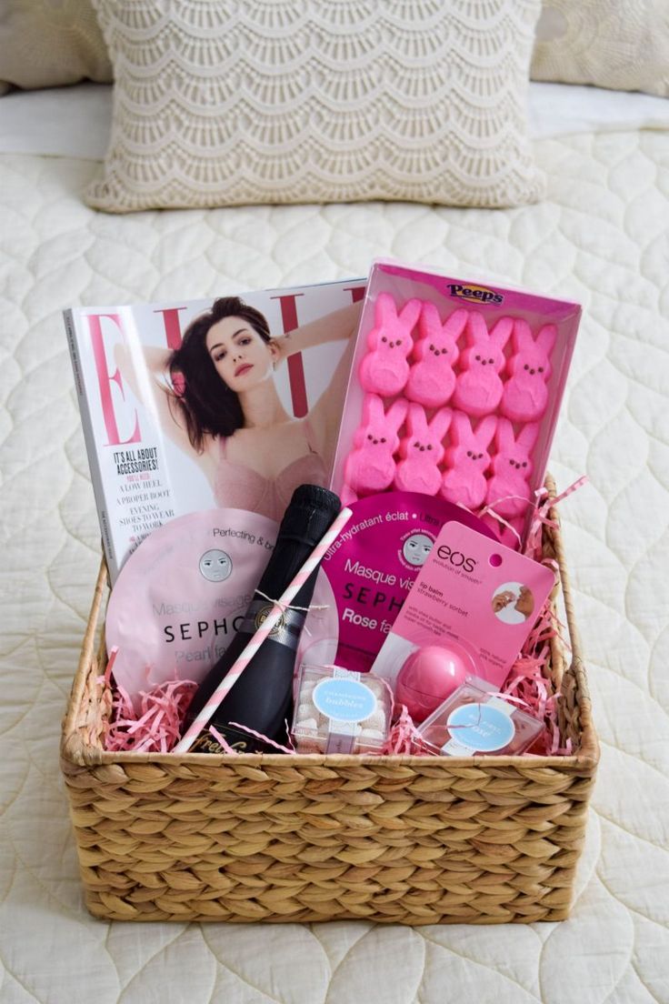 a basket filled with pink items on top of a white bed next to a pillow