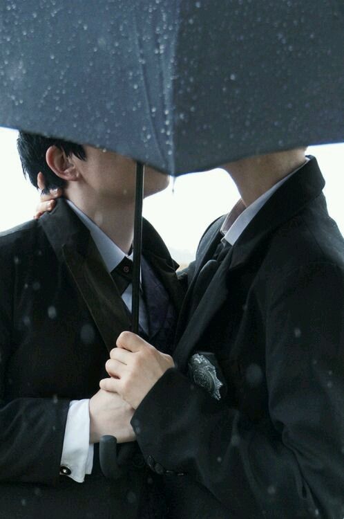 two people are kissing under an umbrella in the rain while it's snowing