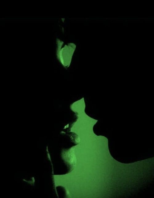 two people are silhouetted against a green background with their heads turned to the side