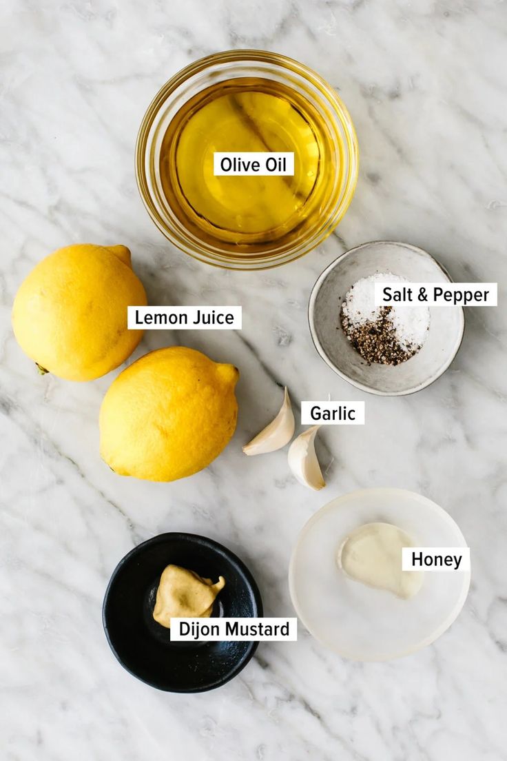 ingredients to make lemon juice on a marble countertop with text overlay that says, olive oil, lemon juice, salt and pepper