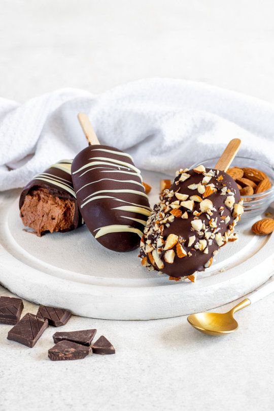 three chocolate covered desserts on a white plate