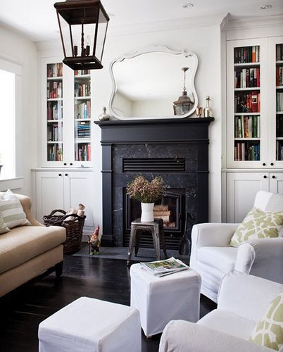 a living room filled with furniture and a fire place in front of a mirror on the wall