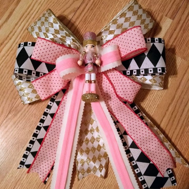 a pink and white bow on top of a wooden floor next to a toy doll