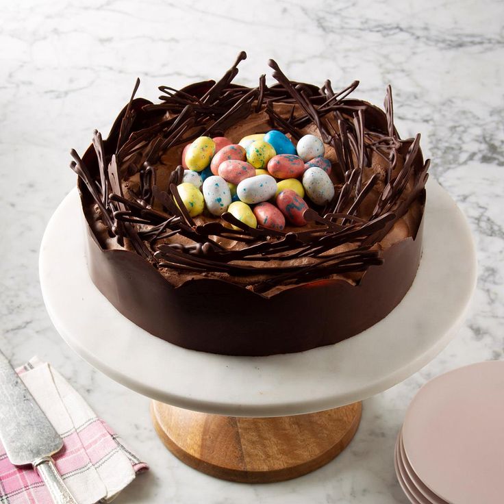 a cake with chocolate icing and colored eggs in the center on a white plate