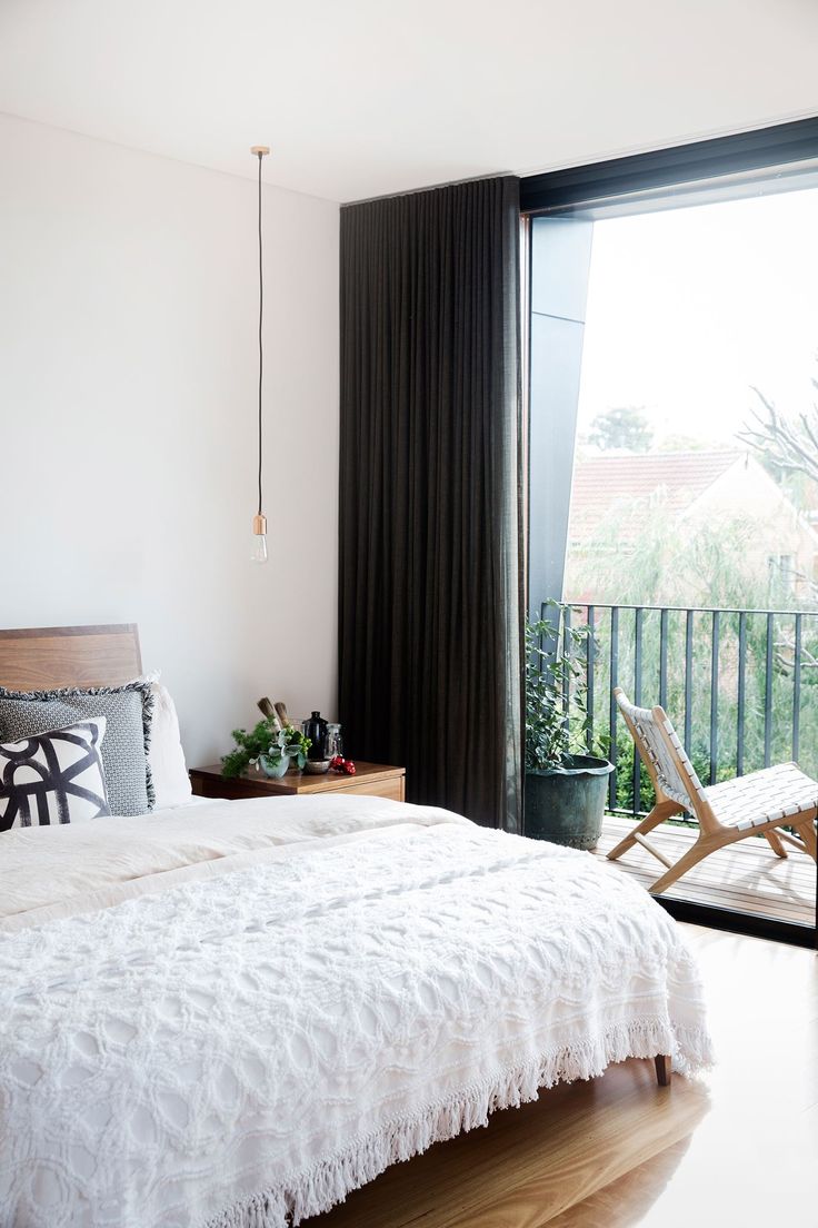 a white bed sitting next to a window in a bedroom