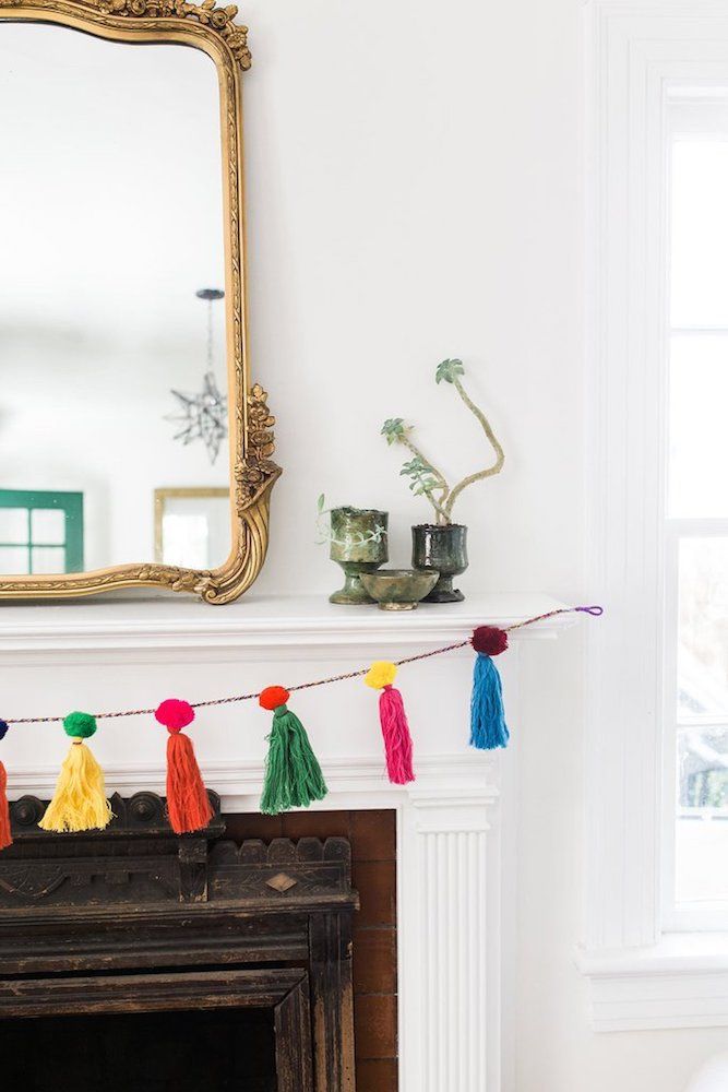 a mantle with a mirror and colorful tassels hanging from it's sides