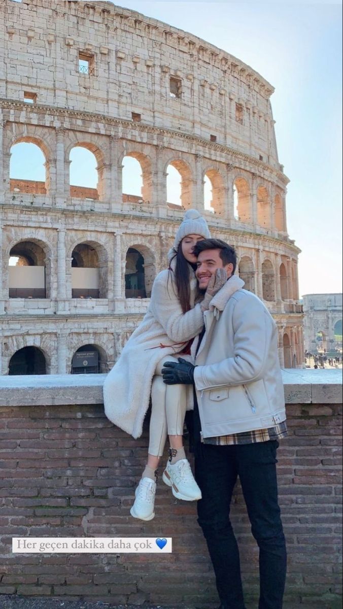 a man and woman posing for a photo in front of the colossion