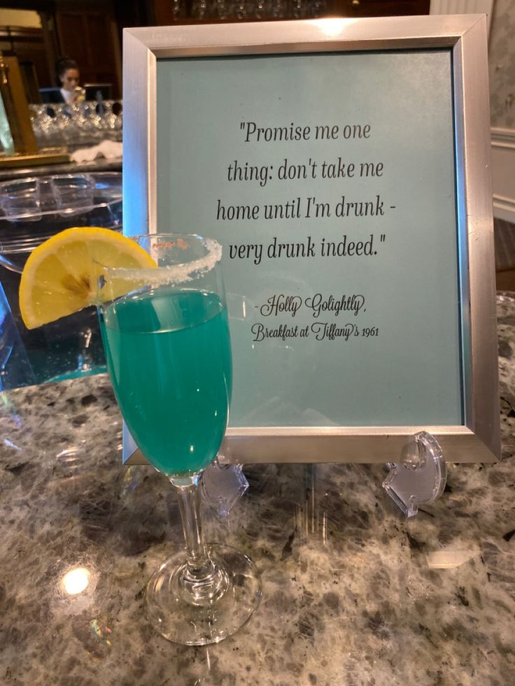 a blue drink sitting on top of a counter next to a framed sign that says, promise me one thing don't take me home until i'm in drunk