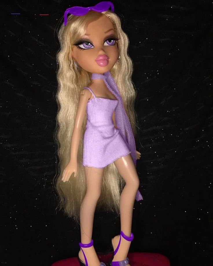 a doll with long blonde hair and purple shoes on top of a red object in the dark