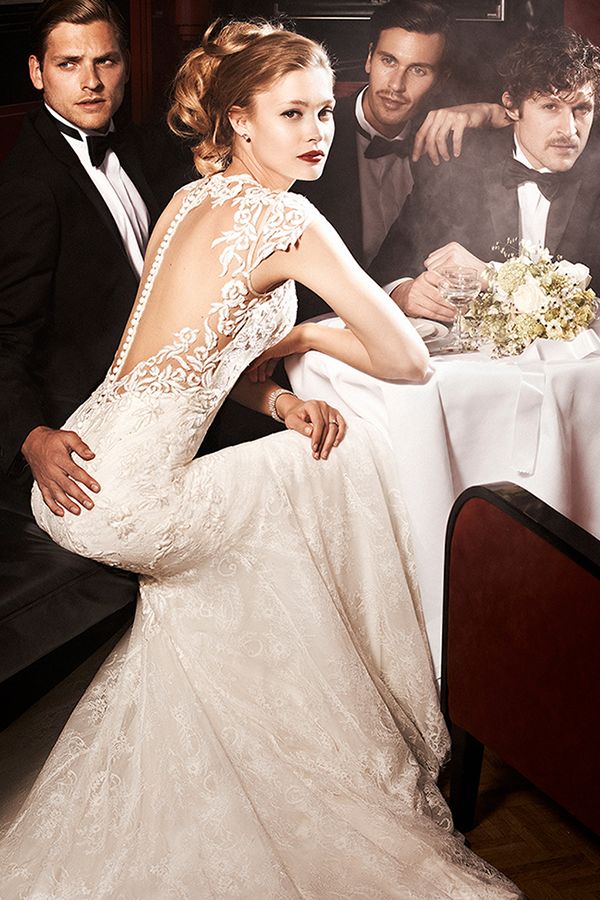 a woman in a wedding dress sitting on a couch with two men standing behind her