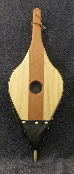 a wooden instrument with black leather straps on a blue cloth covered background and an oval hole in the middle