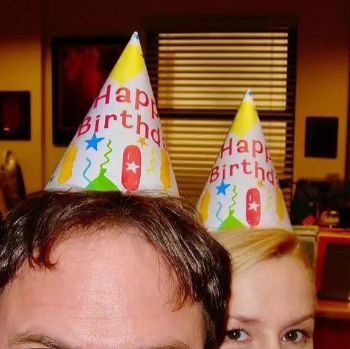 a man and woman wearing birthday hats in an office