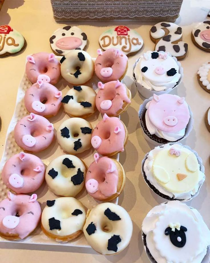 a table topped with lots of cupcakes covered in frosting and farm animals