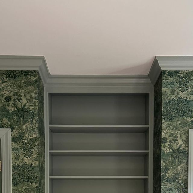 an empty bookcase in the corner of a room with wallpaper on the walls