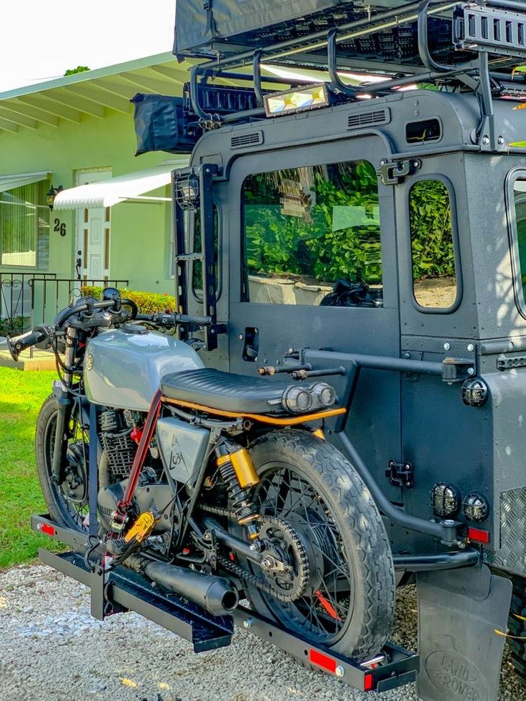 the motorcycle is parked in front of the vehicle with its roof rack attached to it