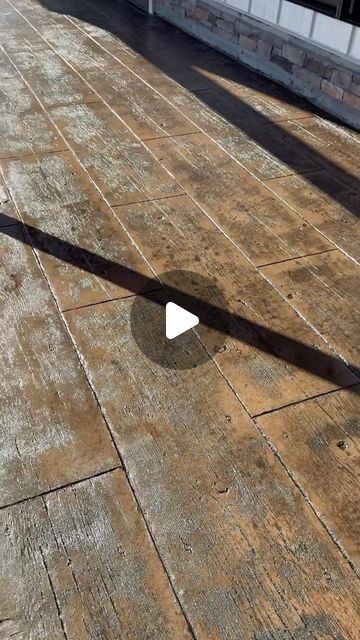 the shadow of a person standing on top of a wooden floor next to a building