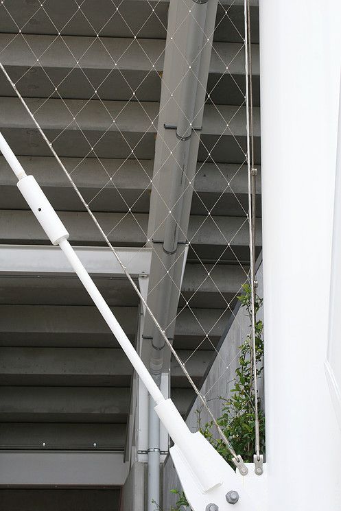 the side of a building that has some wires attached to it and plants growing on top