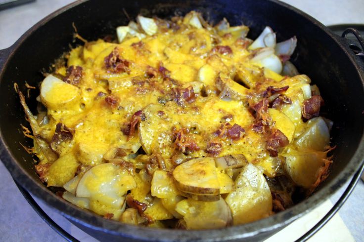 a pan filled with potatoes and bacon on top of a stove next to an oven