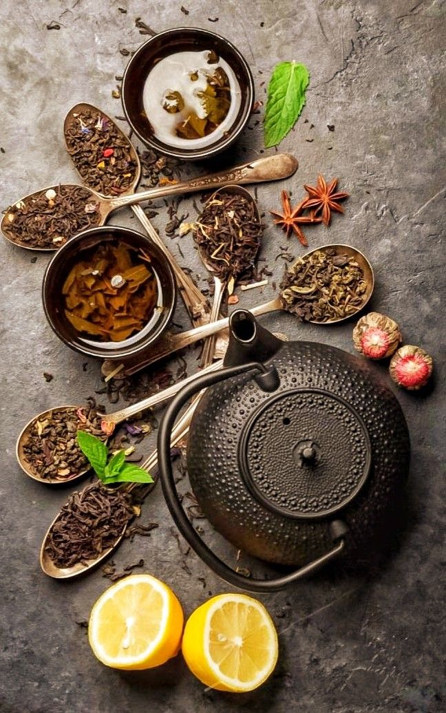 an assortment of teas, lemon slices and spices are arranged on a gray surface