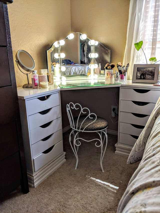 a bedroom with a bed, dresser and mirror on it's side table in front of a window