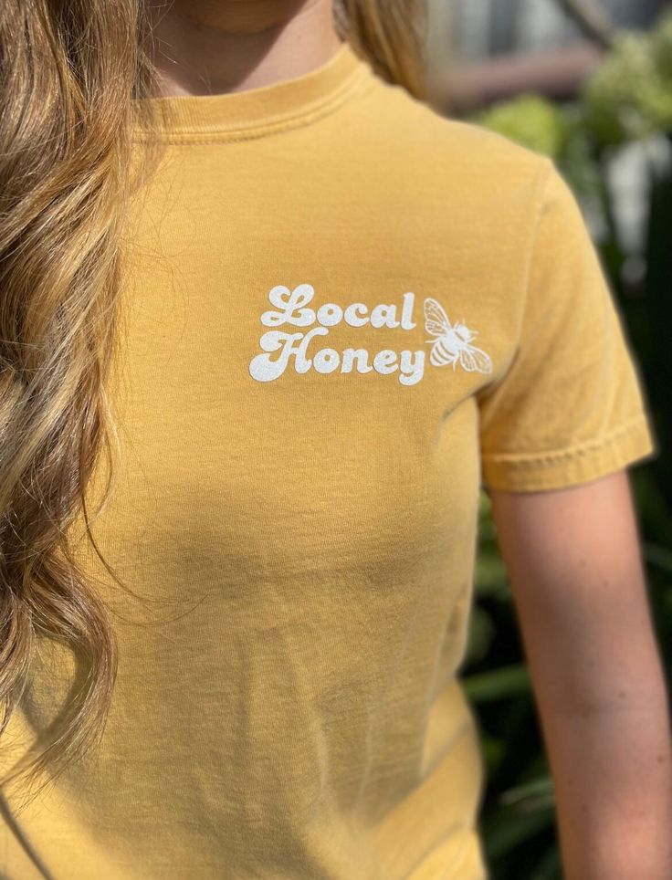 Cute & Comfy Local Honey 🐝 T-shirt ✨Item✨ Unisex t shirt with Local Honey and bee design. Mild yellow colored crew neck shirt with professional heat press lettering  ✨Design✨ you can choose to have the design in plain black or white. Or black or white in glitter. The design in the photos is in Glittler White.  ✨Sizing✨ For best fit, I recommend using the sizing chart. For a loose fit size up. Model in the photo is a size small. These shirts are unisex fit, and fit true to size.  ✨CARE✨ Machine Honey T Shirts, Yellow Short Sleeve T-shirt With Screen Print, Basic Yellow T-shirt With Graphic Print, Yellow Cotton T-shirt With Text Print, Yellow Short Sleeve T-shirt With Text Print, Yellow Crew Neck T-shirt With Screen Print, Yellow Crew Neck T-shirt With Text Print, Retro Yellow T-shirt With Letter Print, Retro Yellow T-shirt With Slogan