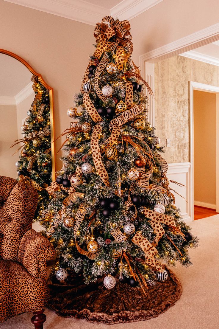 a decorated christmas tree with leopard print ribbon and ornaments on it in a living room