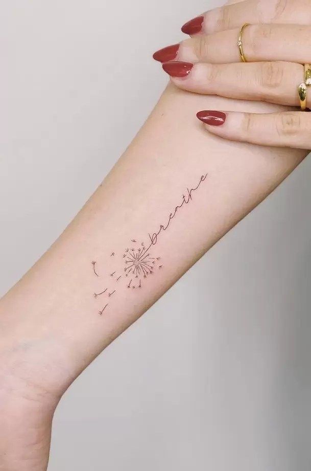 a woman's arm with a dandelion tattoo on the left side of her arm