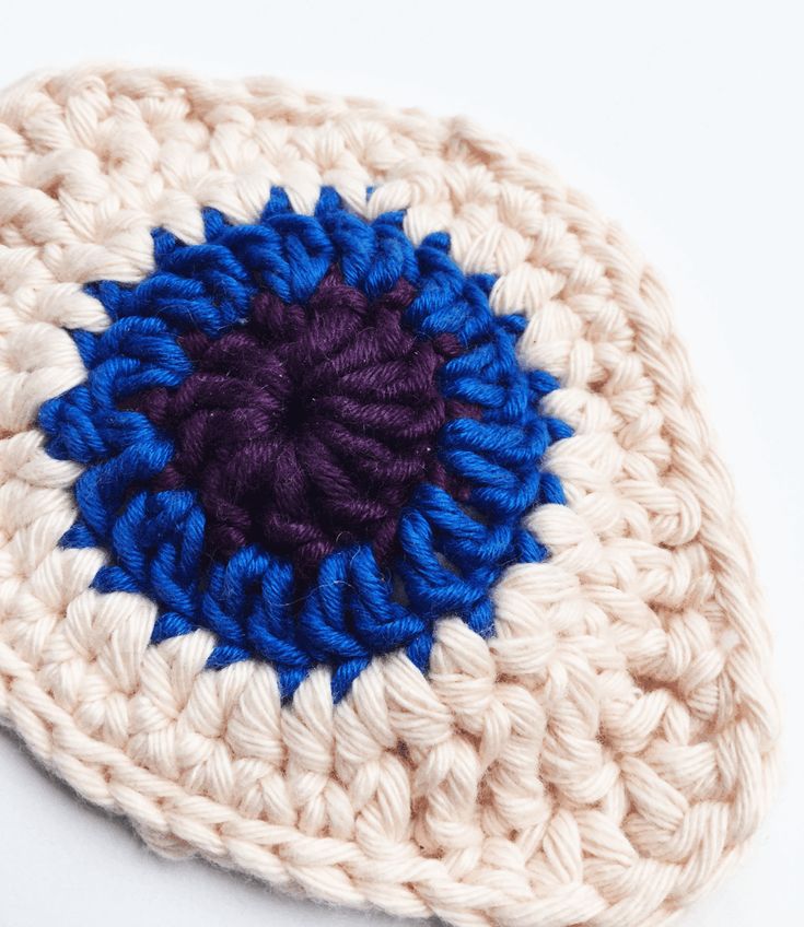 a crocheted hat with a blue and purple circle on it's side