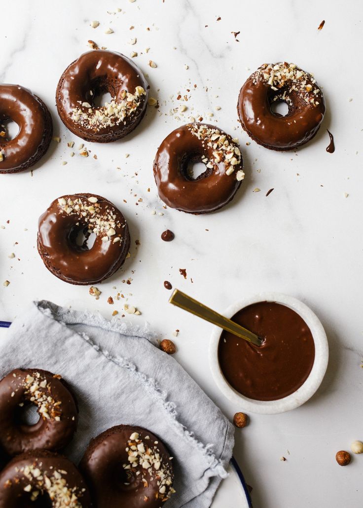 chocolate doughnuts with sprinkles and nuts on a white table top