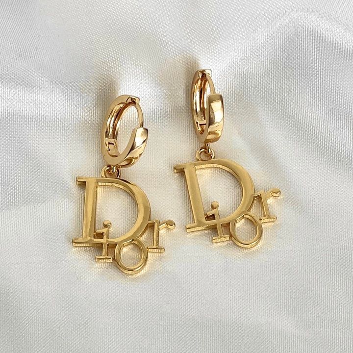 Christian Dior Reworked Gold Dangle Earrings – Reluxe Vintage Trendy Gold Dangle Hoop Earrings, Luxury Gold Huggie Earrings For Gift, Luxury Gold Huggie Earrings As Gift, Tarnish-resistant Gold Dangle Huggie Earrings, Tarnish Resistant Gold Dangle Huggie Earrings, Gold-plated Dangle Huggie Earrings, Luxury Brass Jewelry With Logo Charm, Gold-plated Jewelry With Logo Charm, Luxury Gold Sterling Silver Hoop Earrings