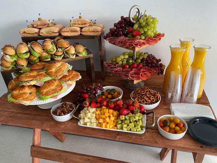 an assortment of food is displayed on a wooden table with plates and bowls full of fruit