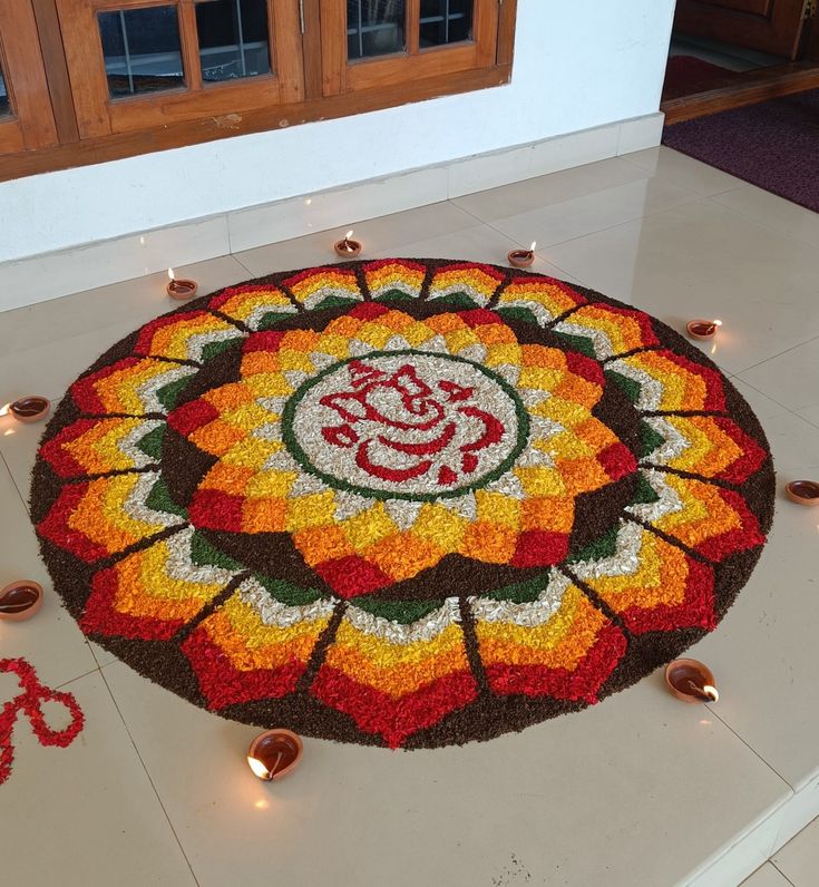 a colorful flower design on the floor with candles around it and an omesh symbol in the center