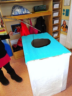 two people standing in front of a blue and white box with a hole on it