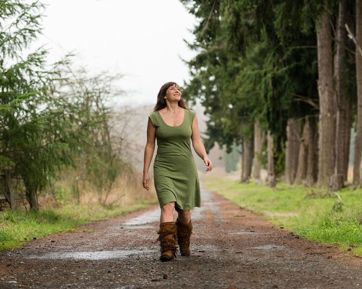 a woman walking down a dirt road in the woods