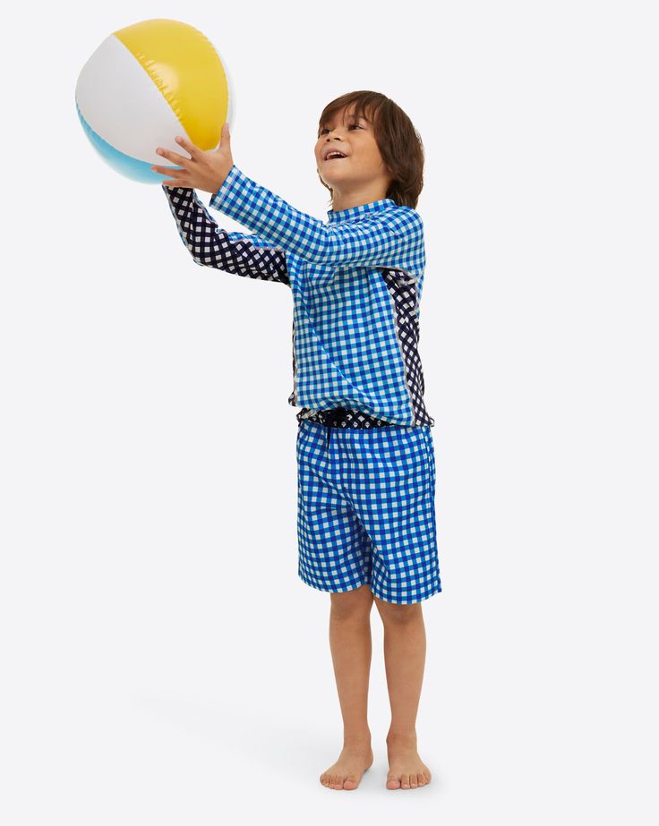 a young boy in blue and white pajamas holding a yellow and white beach ball with both hands