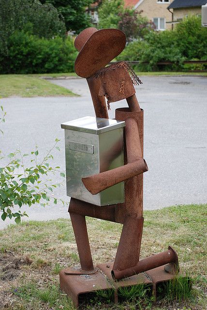 a metal sculpture in the shape of a man holding a mailbox