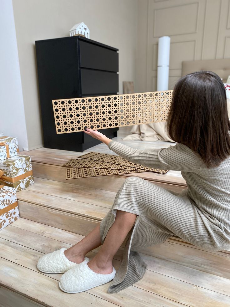 a woman sitting on top of a wooden floor next to a piece of wood cut out