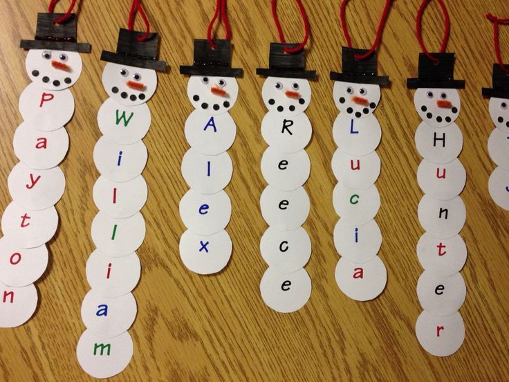 paper snowmen are lined up on the table with name tags attached to their heads