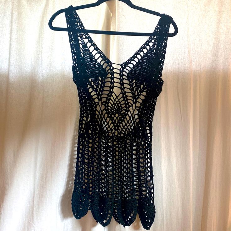 a black crocheted top hanging on a white curtain