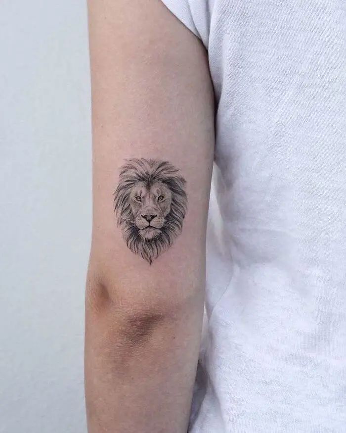 a small lion tattoo on the left upper arm by ide tattocoss