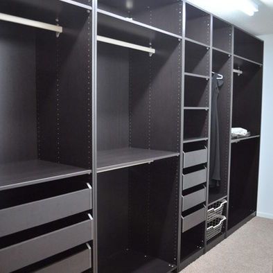 an empty walk in closet with lots of black drawers and bins on the shelves