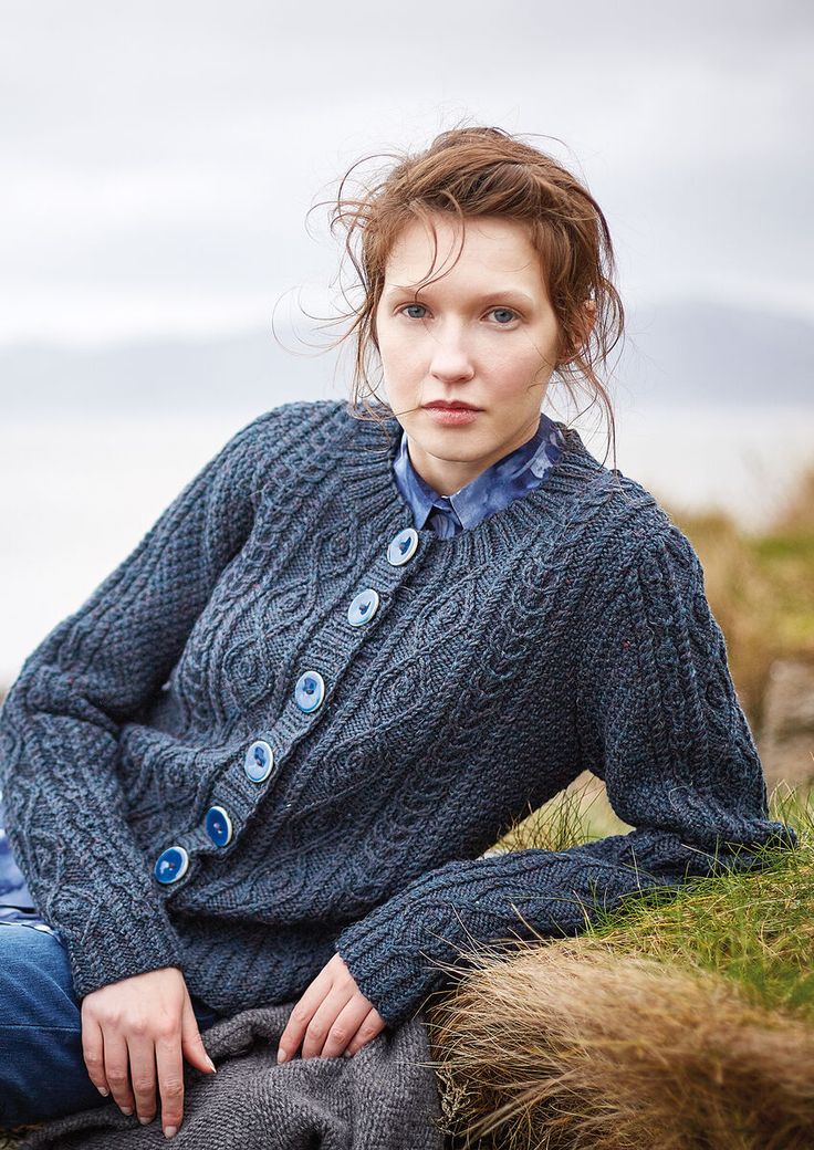 a woman sitting on the ground wearing a blue sweater