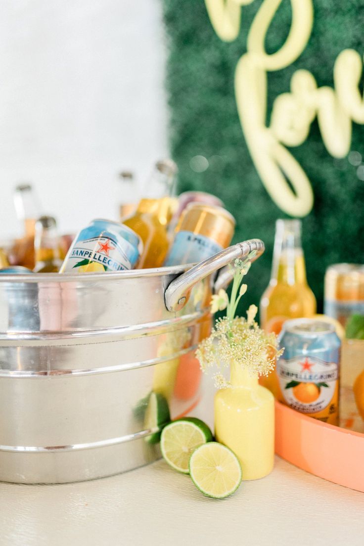 an assortment of drinks are sitting on a table with oranges and limes in the background