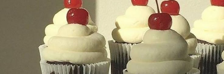 cupcakes with white frosting and cherries on top are arranged in rows